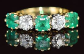 An 18ct gold ring set with three emerald cut emeralds each approximately 0.3ct and two old cut