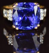 An 18ct gold ring set with a cushion cut tanzanite of approximately 7.85ct with round and baguette