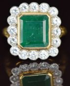 An 18ct gold ring set with an emerald cut emerald of approximately 3.6ct surrounded by sixteen round