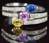 An 18k white gold ring set with oval cut yellow, pink and blue sapphire, each approximately 0.3ct