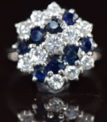An 18ct white gold ring set with round cut diamonds and sapphires in a cluster, the largest