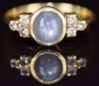 An 18ct gold ring set with a star sapphire cabochon and white sapphires, 4.3g, size O