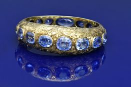 A c1900 18ct gold bangle with engraved floral decoration, set with seventeen natural cushion cut