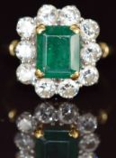 An 18ct gold ring set with an emerald cut emerald of approximately 2.3ct surrounded by ten round cut