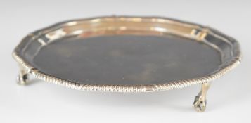 Edward VII hallmarked silver card tray with shaped gadrooned edge, raised on three ball and claw