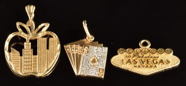 Three 14k gold charms, a hand of cards set with diamonds, 'Welcome to fabulous Las Vegas Nevada' and