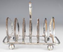 George V hallmarked silver seven bar toast rack with heart shaped hoops and handle, raised on ball