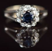 An 18ct gold ring set with a round cut sapphire surrounded by diamonds, 4.6g, size L