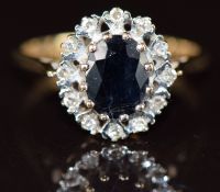 A 9ct gold ring set with an oval cut sapphire surrounded by diamonds, 2.7g, size M