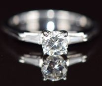 An 18k white gold ring set with a round cut diamond of approximately 0.5ct with a further baguette