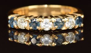 An 18ct gold half eternity ring set with three diamonds and four sapphires, 4.9g, size M