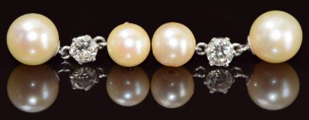 A pair of 18ct white gold earrings each set with a diamond of approximately 0.4ct and two cultured