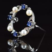 A 9ct white gold brooch set with round cut sapphires and cultured pearls, with foliate decoration,