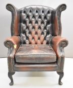 Brown leather Chesterfield wing back armchair raised on cabriole legs, height 105cm