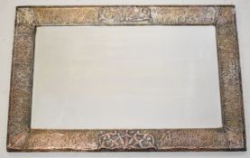 Arts & Crafts copper framed mirror with hammered and relief moulded decoration and bevelled glass