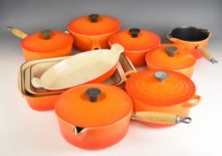 Ten items of Le Creuset cast iron cook ware in Volcanic Orange, to include lidded saucepans, milk