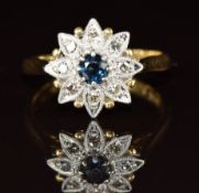An 18ct gold ring set with a sapphire surrounded by diamonds in a floral platinum setting, 3.2g,