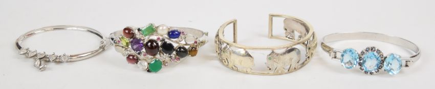 Three silver bangles including one in the form of elephants set with emerald eyes, one set with an
