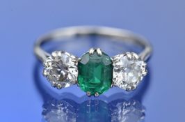 A platinum ring set with an emerald cut emerald of approximately 1.1ct and two old cut diamonds of