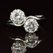 A platinum ring set with two round cut diamonds of approximately 1ct and 1.1ct in a twist setting,
