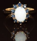 A 9ct gold ring set with an opal surrounded by sapphires, 4.1g, size P
