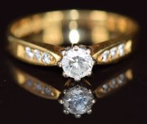 An 18ct gold ring set with a round cut diamond of approximately 0.2ct and with further diamonds to