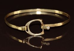 A 10k gold bangle in the form of a stirrup set with a diamond, 7g