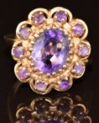 A 14k gold ring set with an oval cut amethyst surrounded by further round cut amethysts, 5g, size L
