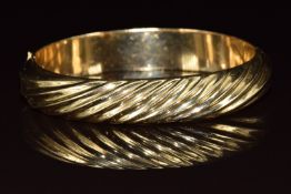 A 14k gold bangle with ridged decoration, 18.4g, 5.6 x 5.2cm