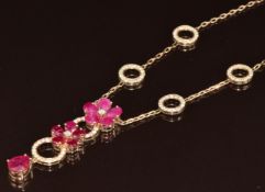 A 14k gold ruby and diamond necklace consisting of two circular flower cluster heads set with