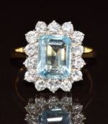An 18ct gold ring set with an emerald cut aquamarine of approximately 2ct surrounded by diamonds,
