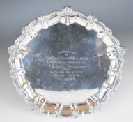 George V hallmarked silver salver with shaped edge, raised on three ball and claw feet, Birmingham