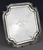 George V hallmarked silver salver of square form with incuse corners, raised on four feet, London