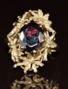 A 9ct gold ring set with an oval cut garnet with a textured setting, 5.1g, size K