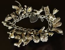 A silver charm bracelet with twenty one charms including frog, the moon opening to reveal an