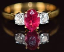 An 18k gold ring set with an oval cut ruby of approximately 1ct and two round cut diamonds, each