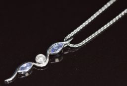 A platinum pendant set with two marquise cut tanzanites and a round cut diamond of approximately 0.