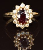 A 9ct gold ring set with an oval cut garnet surrounded by cubic zirconia, 2.9g, size M
