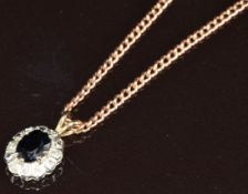 A 9ct rose gold chain (46cm) and a 9ct gold pendant set with an oval cut sapphire surrounded by