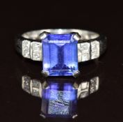 A platinum ring set with an emerald cut tanzanite of approximately 3.4ct and four princess cut