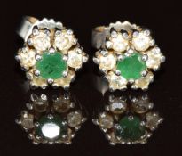 A pair of white metal earrings each set with an emerald surrounded by diamonds in a cluster, 2.2g
