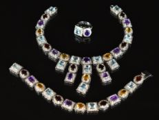 A suite of white metal jewellery comprising necklace, bracelet and ring set with topaz, garnets,