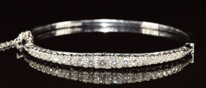 An 18ct white gold bangle set with graduating round cut diamonds, the largest approximately 0.