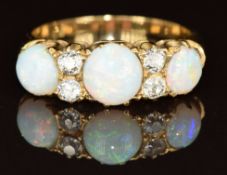 A c1910 18ct gold ring set with three round opal cabochons and four old cut diamonds, each diamond