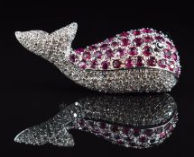 An 18k white gold brooch in the form of a whale set with rubies, diamonds and a sapphire eye,