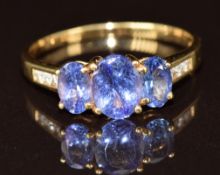 An 18ct gold ring set with three oval cut tanzanites totalling 2ct and diamonds, 4g, size T