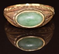 Victorian yellow metal ring set with a jadeite cabochon with engraved decoration to the shoulders,