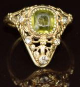 Arts & Crafts yellow metal ring set with a cushion cut peridot and diamonds in a pierced setting,