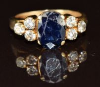 An 18ct gold ring set with an oval cut sapphire of approximately 1.8ct and three diamonds to each