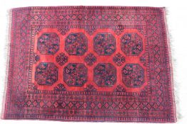 A black and red Bokhara rug with fringed ends.